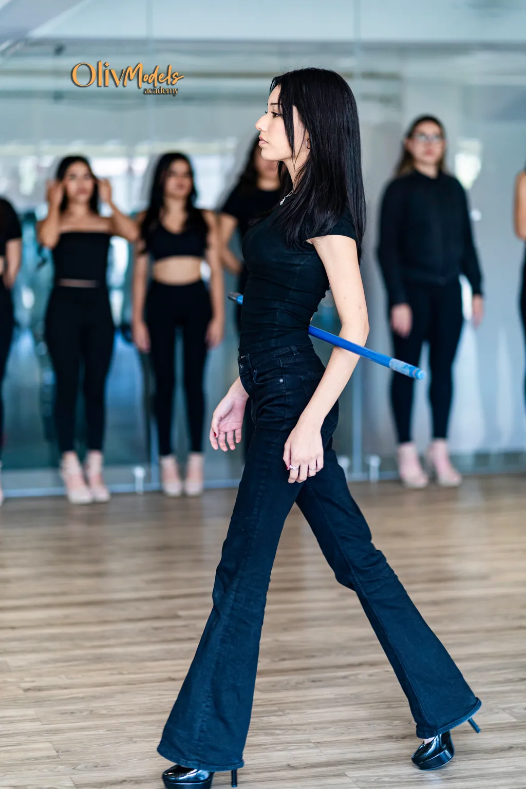 Modelo caminando en pasarela con grupo Oliv Models al fondo